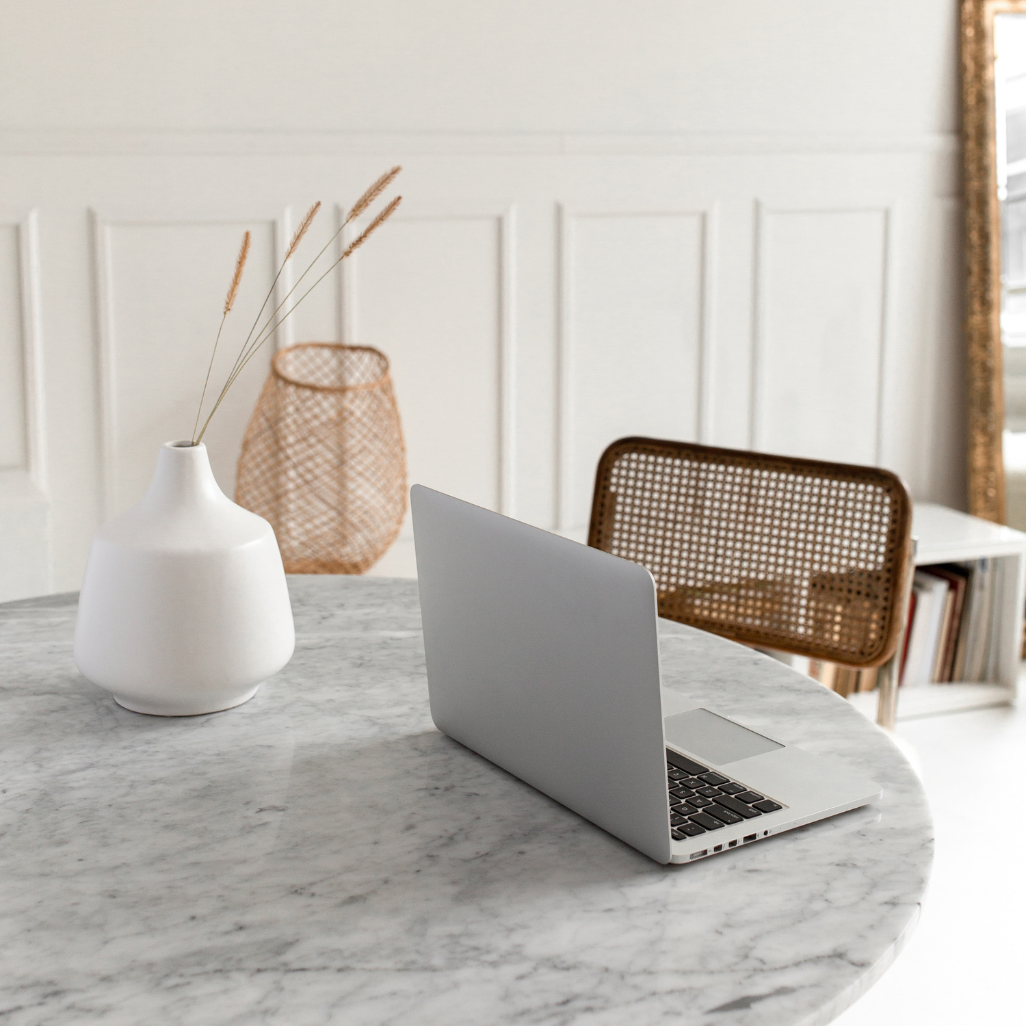 laptop open on the desk of a creative business owner, with ceramic vase and dried flowers.
