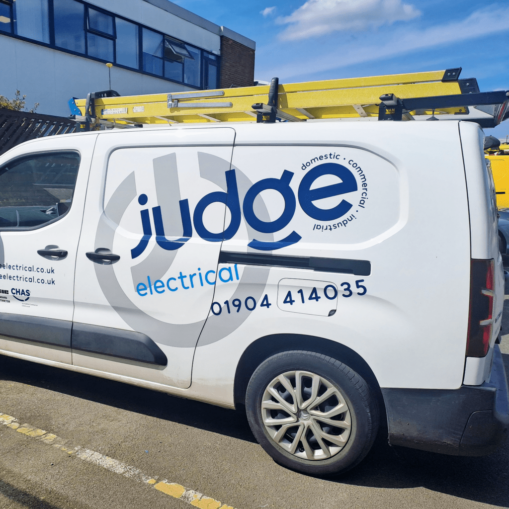 White tradesmans van with large blue logo and grey submark that reads Judge Electrical parked outside business premises