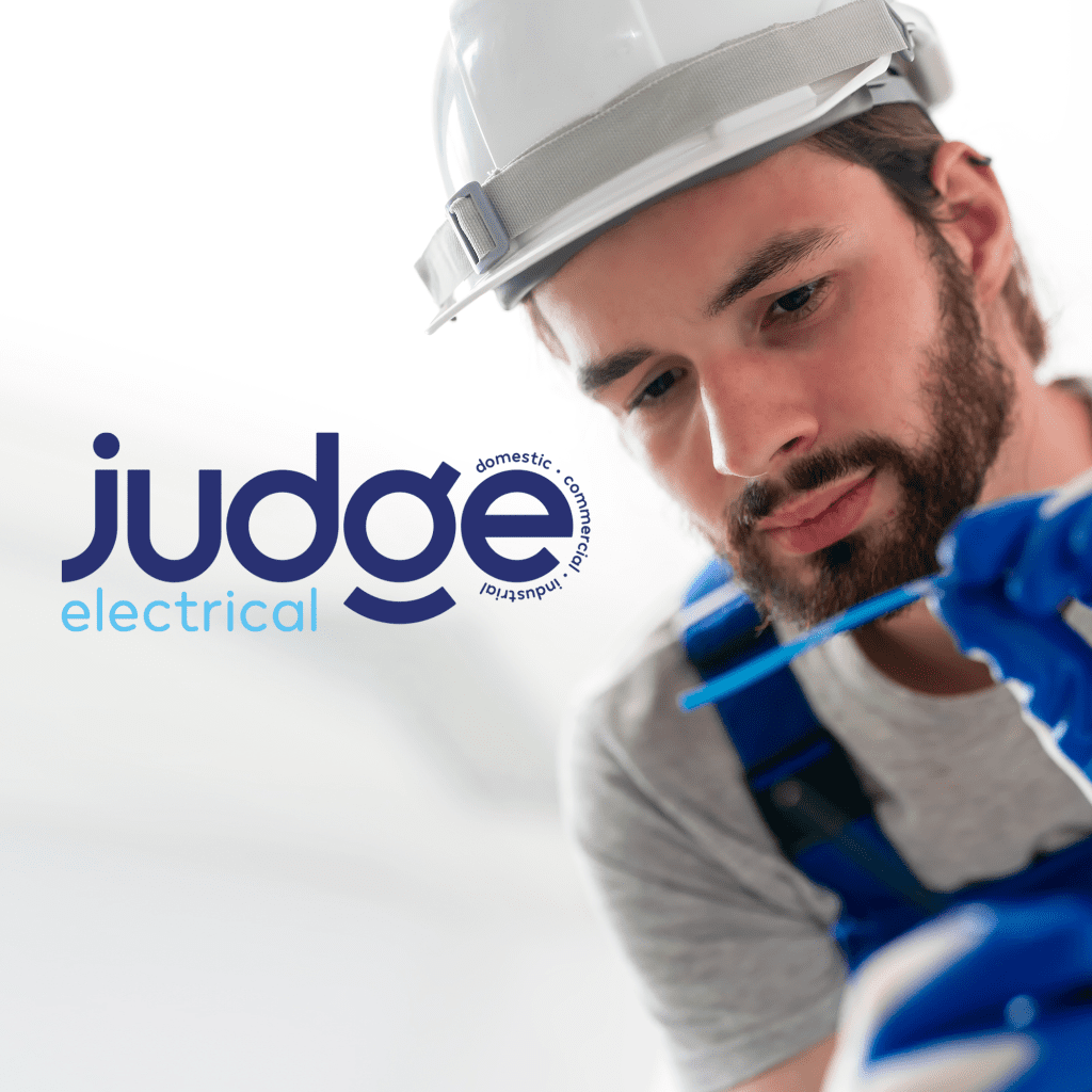 Man in a hard hat carrying out electricians duties with logo for Judge electrical in blue in the top corner