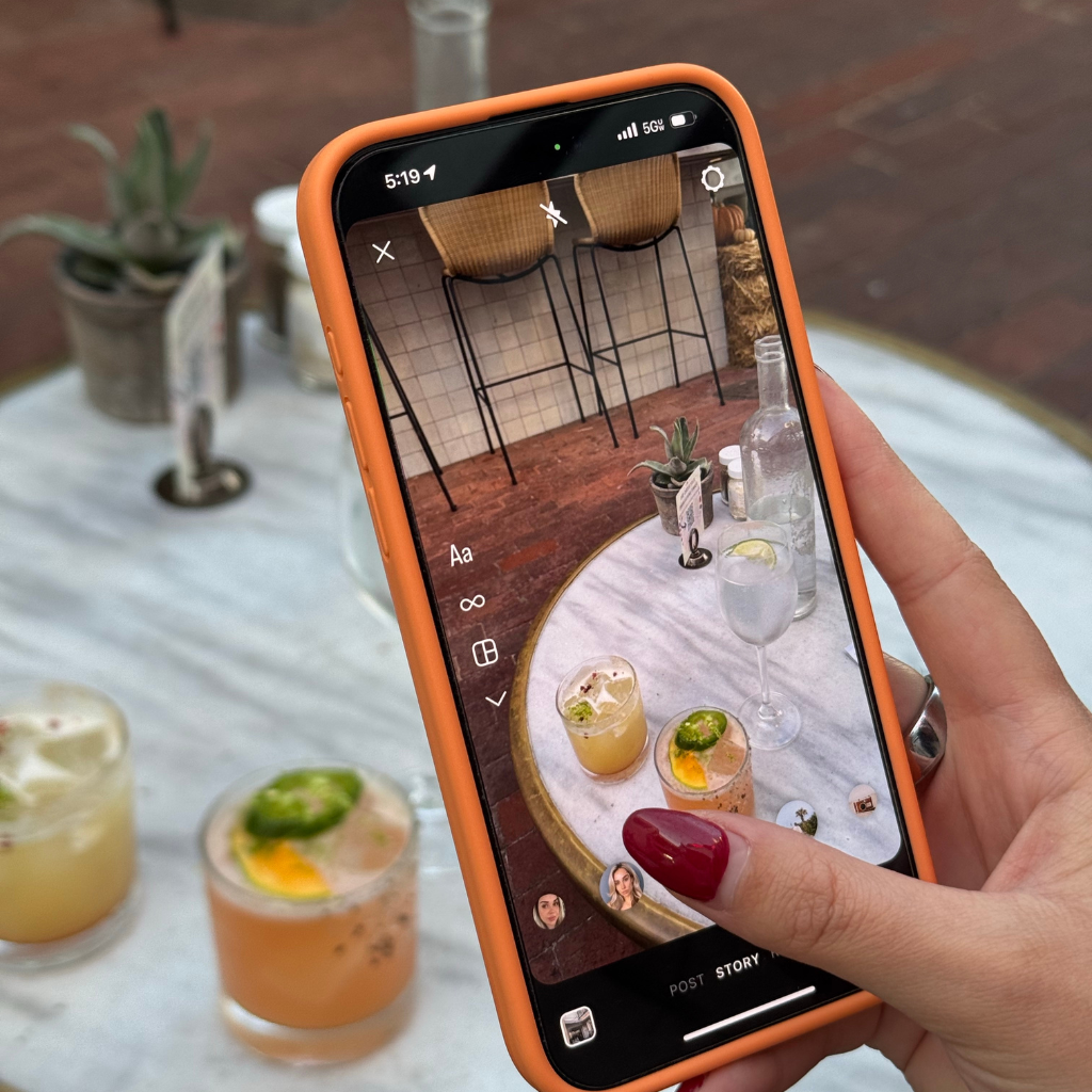York website designer taking photo of drinks on a table on phone for social media