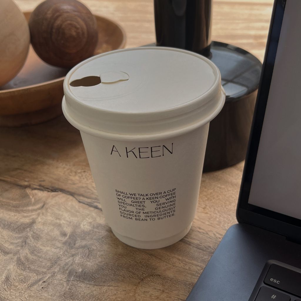 Recycled coffee cup showing coffee shop branding and logo on side of the cup