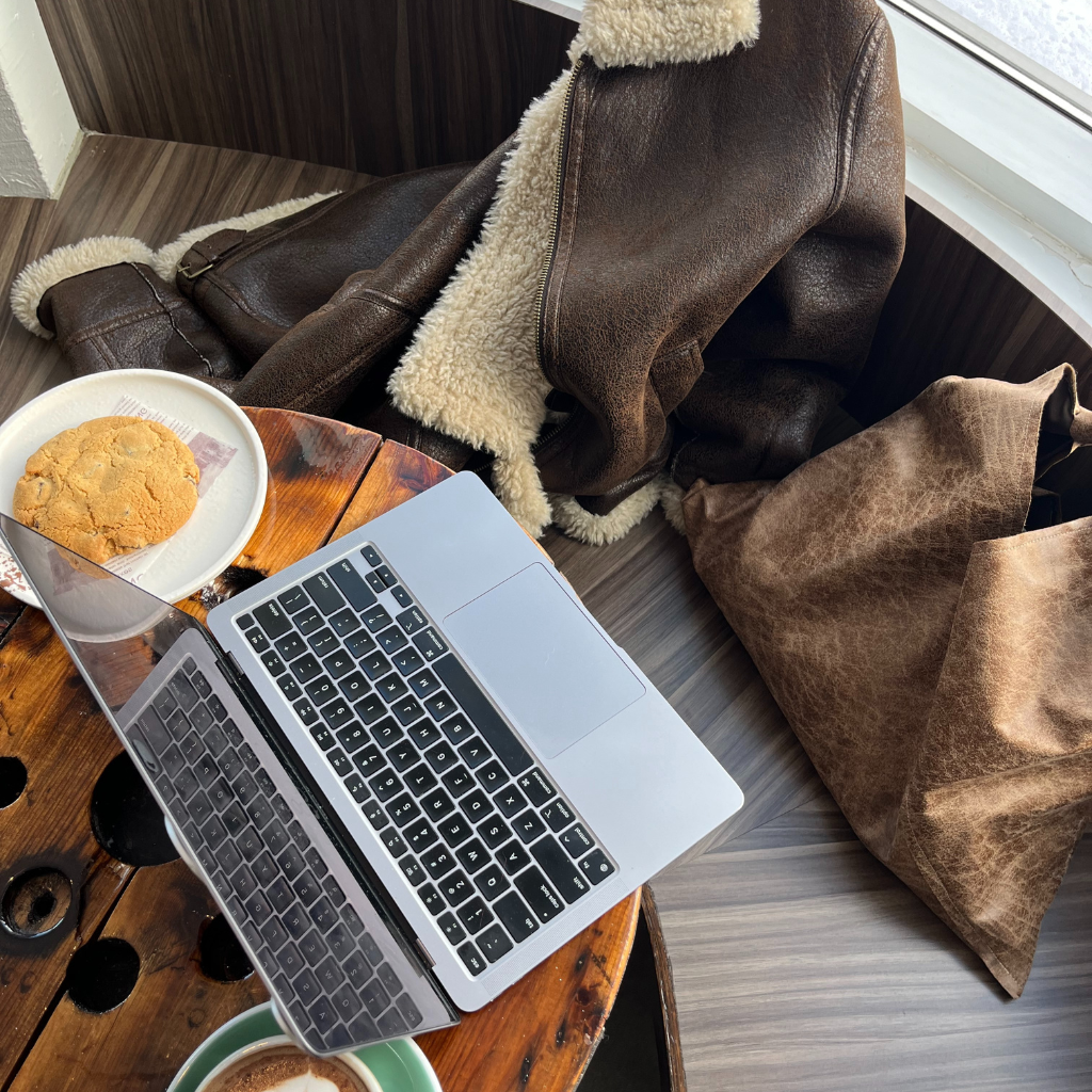 Open laptop on a cafe table with coffee and cookie to design a visitor first website design